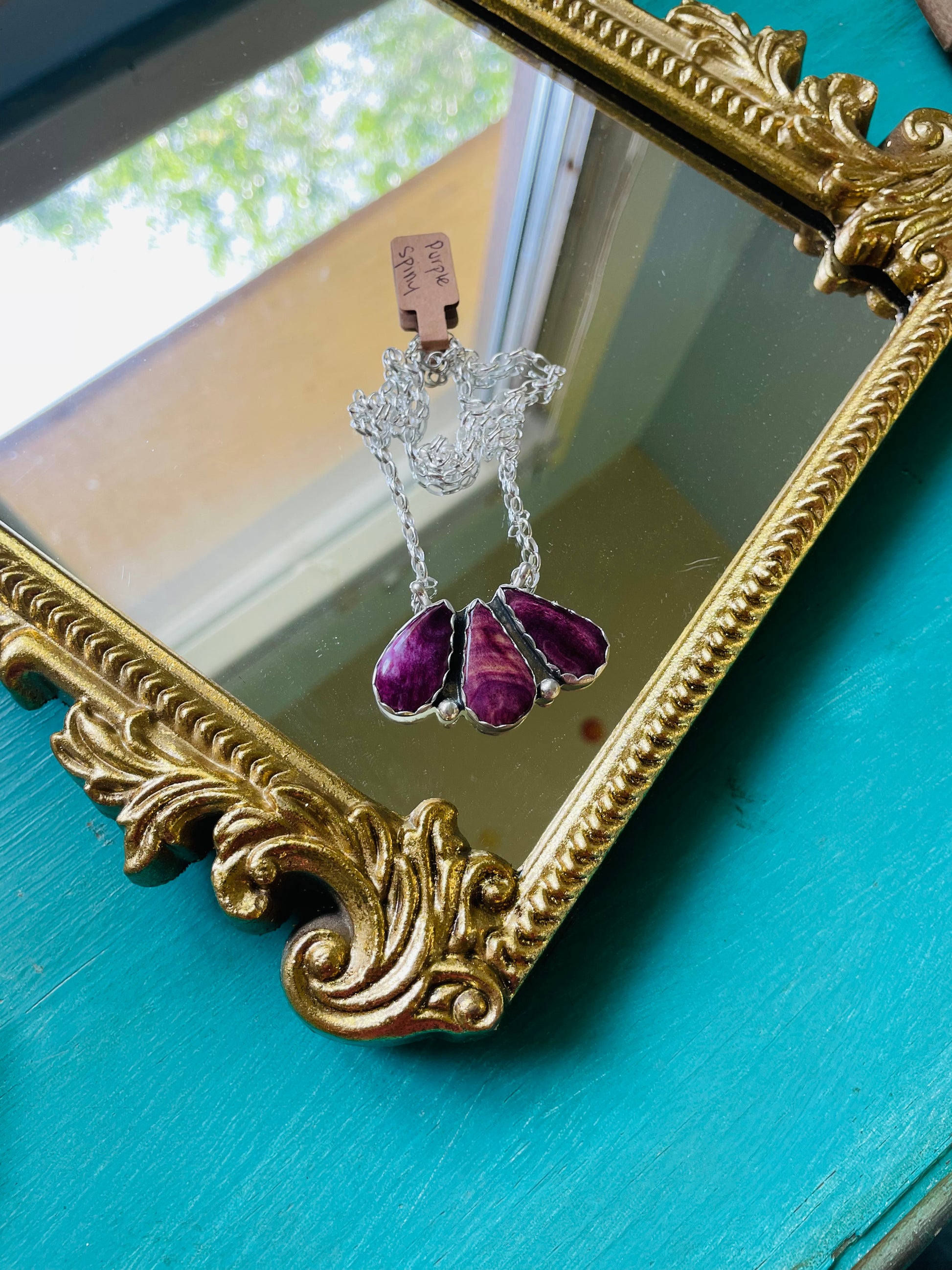 3 purple spiny oyster stones set in sterling silver on a sterling silver 18” chain resting on a gold mirror 