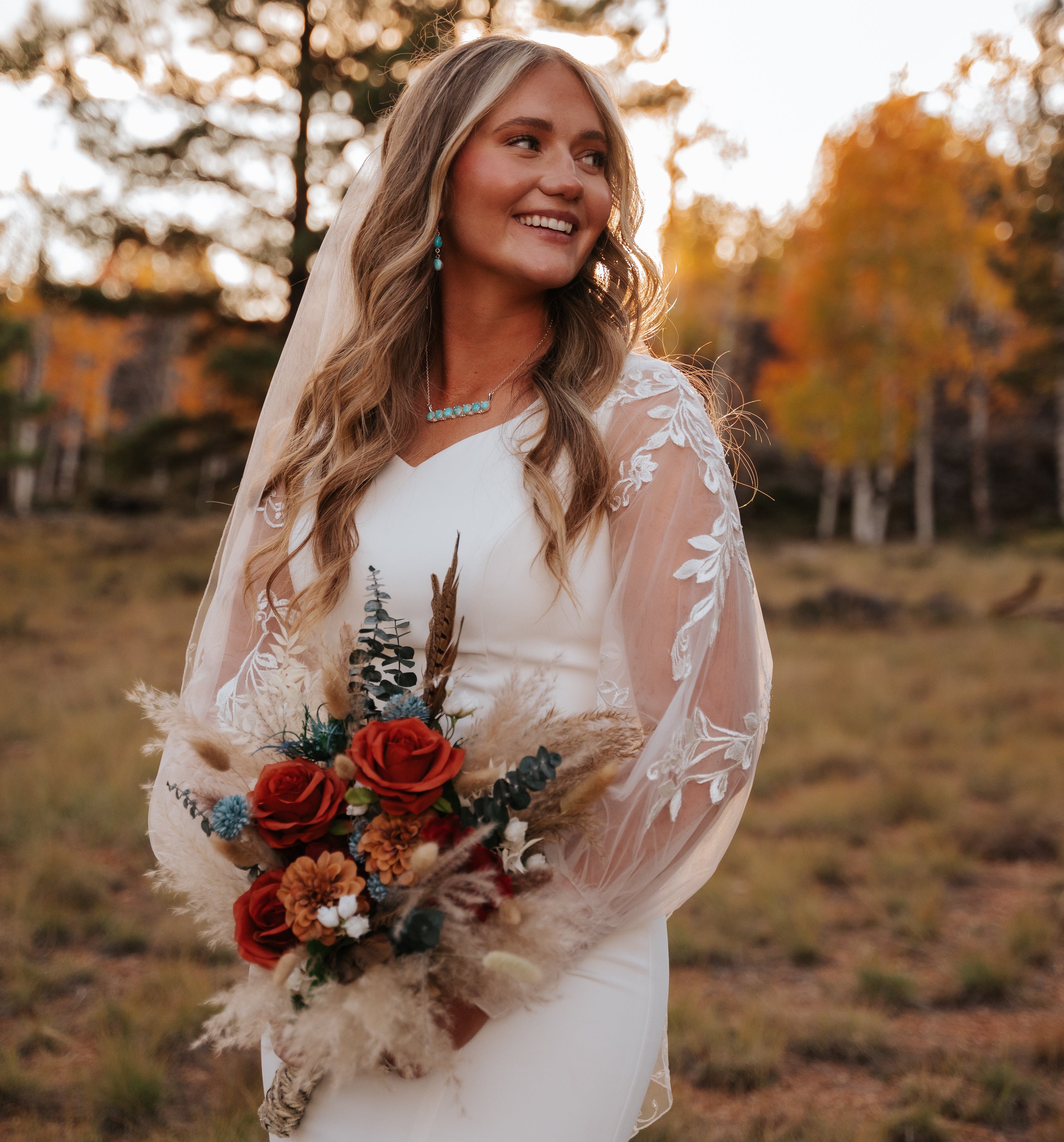 Bride holding a bouquet in a natural setting with trees and grass.